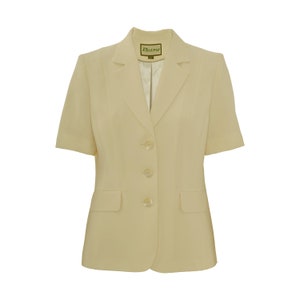 May include: A cream-colored short-sleeved blazer with a button closure and a pocket on each side. The blazer has a label that says "Busy" on the inside collar.