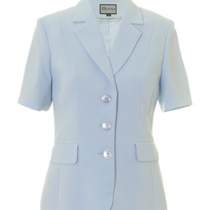 May include: A light blue blazer with short sleeves and four silver buttons. The blazer has a label that says "Busy" on it.
