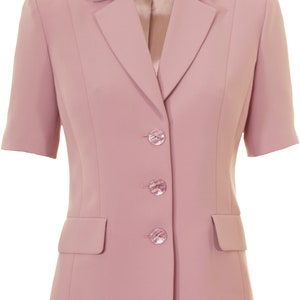 May include: A pink short-sleeved blazer with a notched collar and three buttons. The blazer has a pocket on the left side and a label that says "Busy" on the collar.