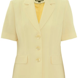 May include: A pale yellow short-sleeved blazer with four buttons and a pocket on the left side. The blazer has a label that says "Busy" on it.