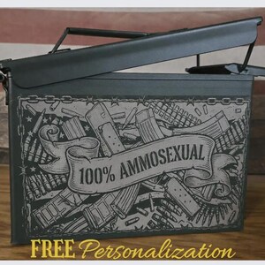 May include: A matte black metal ammunition storage box with a hinged lid. The front features a laser-engraved graphic of various firearm magazines and cartridges, centered with a banner containing the text 100% AMMOSEXUAL in capital letters.