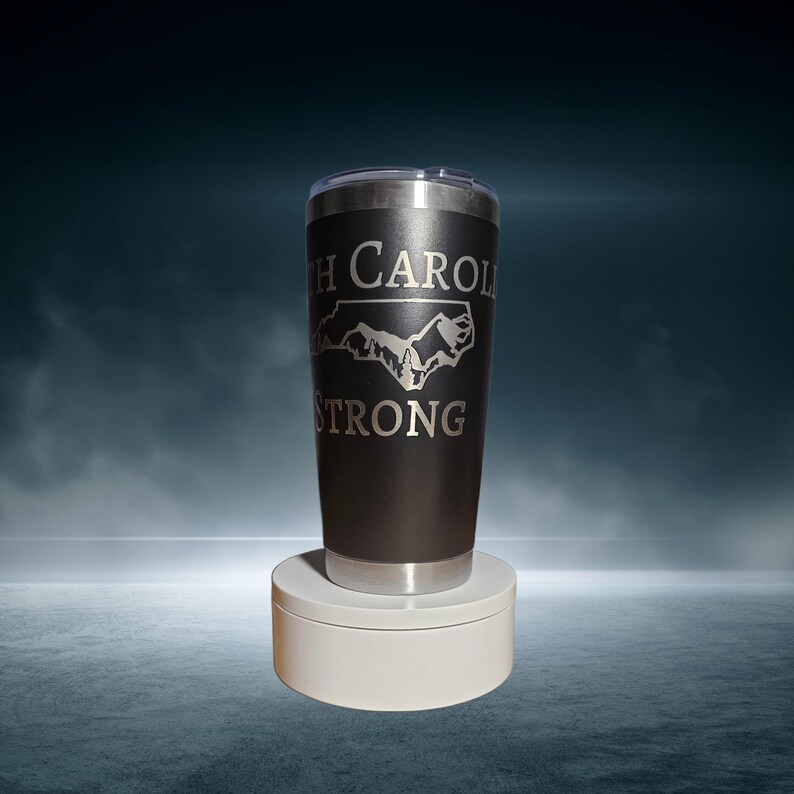 May include: A black stainless steel tumbler with a white outline of the state of North Carolina and the text "North Carolina Strong".