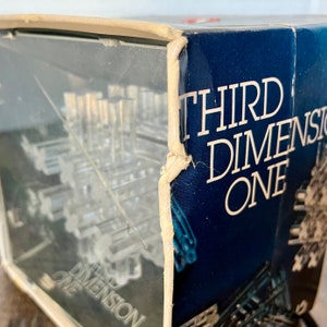 May include: A vintage box for a 3D puzzle game called "Third Dimension One". The box is blue with white lettering and shows a glimpse of the puzzle inside.
