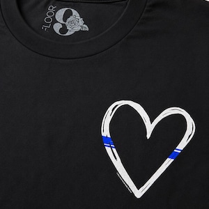 May include: A black t-shirt featuring a white hand-drawn heart outline on the front. The heart includes a thin blue horizontal stripe detail. The inner neck label displays the text 9 FLOOR with a rose graphic and additional small text.