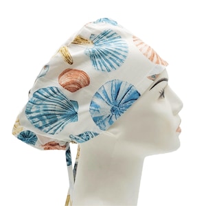Puede incluir: Un gorro quirúrgico blanco con un patrón de conchas azules y marrones.