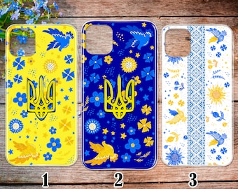 May include: Three phone cases with different designs featuring the Ukrainian coat of arms, a yellow trident on a blue background. The first case has a yellow background with blue flowers and stars. The second case has a blue background with yellow flowers and stars. The third case has a white background with blue and yellow floral patterns and a traditional Ukrainian embroidered design.