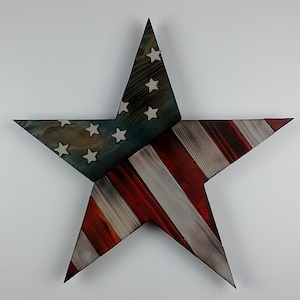 May include: A large wooden star, painted to resemble the American flag. The star features the blue field with white stars and red and white stripes. The rustic design is suitable for patriotic decor.
