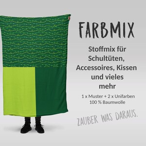Könnte beinhalten: Ein grüner Stoff mit einem gelben und grünen Muster, beschriftet mit "FARBMIX" und beschrieben als Stoffmix für Schultüten, Accessoires, Kissen und vieles mehr. Der Stoff ist 100% Baumwolle und beinhaltet ein Muster und zwei unifarbene Stoffe. Der Text "ZAUBER WAS DARAUS" ist ebenfalls sichtbar.