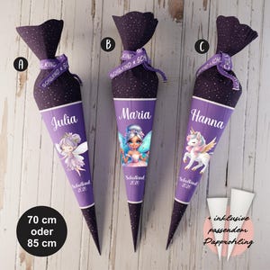Könnte beinhalten: Drei lila-schwarze Schultüten mit verschiedenen Designs. Eine Tüte hat eine Feenillustration und den Namen "Julia", eine andere eine Feenillustration und den Namen "Maria", und die dritte eine Einhornillustration und den Namen "Hanna". Die Tüten sind 70 cm oder 85 cm hoch.