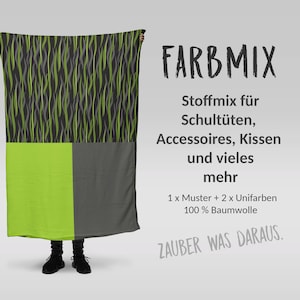 Könnte beinhalten: Eine Person hält einen Stoff in Grün und Grau mit einem Flammenmuster. Der Stoff ist mit "FARBMIX Stoffmix für Schultüten, Accessoires, Kissen und vieles mehr 1 x Muster + 2 x Unifarben 100% Baumwolle ZAUBER WAS DARAUS." beschriftet.