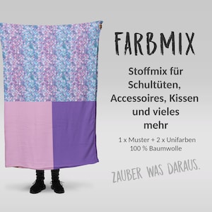 Könnte beinhalten: Eine Person hält ein Stoffmuster mit einem bunten Muster in Blau, Rosa und Lila hoch. Der Stoff wird als Mischung für Schultüten, Accessoires, Kissen und mehr beschrieben. Er besteht aus 100% Baumwolle und beinhaltet ein Muster und zwei unifarbene Stoffe. Der Text "FARBMIX" befindet sich oben im Bild, und der Text "ZAUBER WAS DARAUS." befindet sich unten.