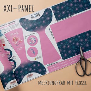 Könnte beinhalten: Ein rosa-blaues Stoffpaneel mit einem Meerjungfrauenschwanz-Design, mit dem Text "XXL-PANEL" und "CUT & SEW". Enthält Illustrationen von Meerjungfrauen, Delfinen und Seepferdchen. Eine Schere liegt rechts auf dem Panel.
