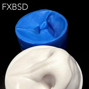 Puede incluir: Un molde de silicona blanco de una nariz humana, con una superficie texturizada. El molde está sentado sobre un molde de silicona azul.