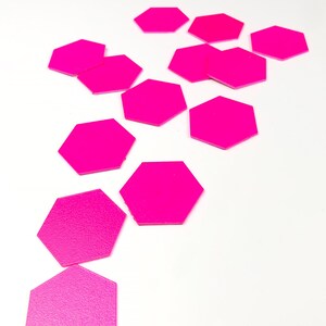 May include: A collection of 12 bright pink hexagonal shaped stickers. The stickers are scattered on a white surface. The text "FX BSDESIGN" is visible in the bottom right corner of the image.