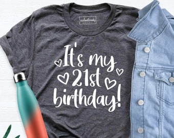 May include: A dark gray t-shirt with the text "It's my 21st birthday!" in white lettering with small hearts around the text.