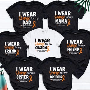 May include: Six black and white t-shirts with orange ribbons and the text "I wear orange for my" followed by a family member, such as "dad", "mama", "friend", "custom", "sister", or "brother". The text also includes "Multiple Sclerosis Awareness".