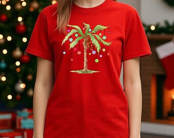 May include: A bright red short-sleeved t-shirt featuring a graphic of a green palm tree decorated with colorful hanging ornaments. The design includes the text "coolandtrendy DESIGN" in the upper right corner of the image.