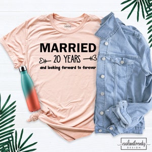 May include: A pink t-shirt with the text "MARRIED 20 YEARS and looking forward to forever" printed in black.