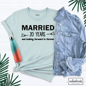 May include: A light blue t-shirt with black text that reads "Married 20 Years and looking forward to forever".