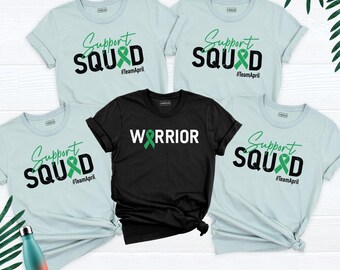 May include: Four light blue t-shirts with the text Support SQUAD and a green ribbon, plus one black t-shirt with the text WARRIOR and a green ribbon. All shirts feature the hashtag #TeamApril. A gradient orange and blue water bottle is included.