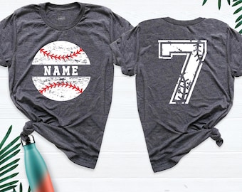 May include: A dark heather gray short-sleeve t-shirt featuring a white baseball graphic with red stitching and the word NAME on the front, and a large white number 7 with baseball stitching details on the back of the garment.