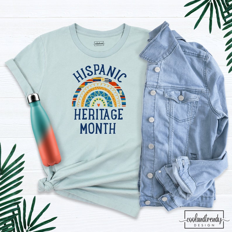 May include: A light blue t-shirt with a rainbow design and the text "Hispanic Heritage Month".