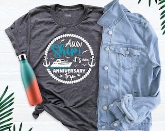 May include: A dark gray heather t-shirt with a white and blue graphic featuring a cruise ship, anchors, and the text AWW SHIP! IT'S AN ANNIVERSARY TRIP, paired with a light blue denim jacket and a teal and orange gradient metal water bottle.