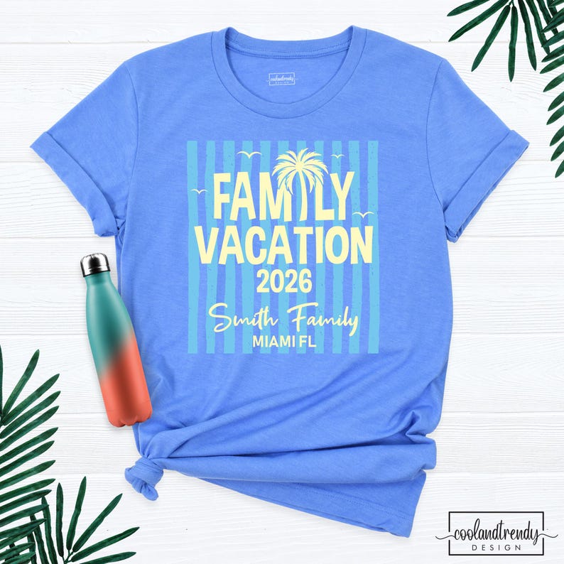 May include: A light blue short-sleeve t-shirt featuring a graphic with vertical stripes, a palm tree, and the text FAMILY VACATION 2026, Smith Family, and MIAMI FL in yellow. A gradient teal and orange water bottle is positioned on the left side.