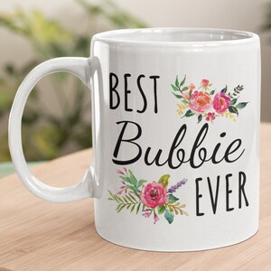 May include: White ceramic mug with a black floral design and the text 'Best Bubbie Ever'.