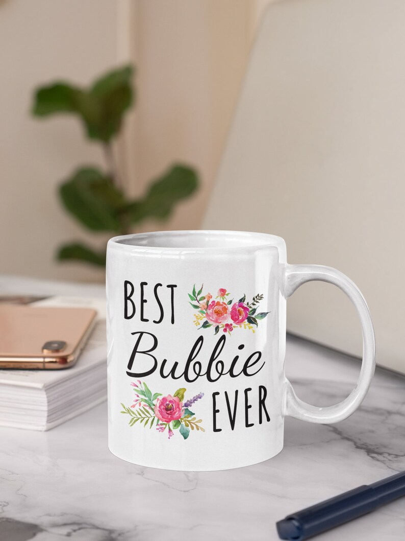 May include: White ceramic mug with a black floral design and the text "Best Bubbie Ever".