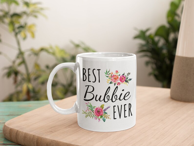 May include: White ceramic mug with a black floral design and the text 'Best Bubbie Ever'.