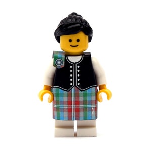 May include: A Lego minifigure dressed in traditional Scottish attire. The figure has a yellow head with a smiling face and black hair. It wears a black vest, a tartan kilt in red, green, and blue, and a white shirt.