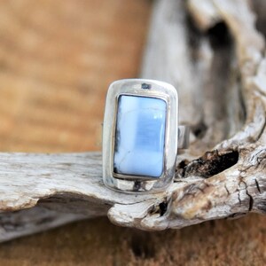May include: A silver ring with a light blue rectangular stone set in a bezel setting.