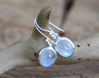 May include: A pair of silver dangle earrings with moonstone gemstones. The earrings have a simple design and are perfect for everyday wear.