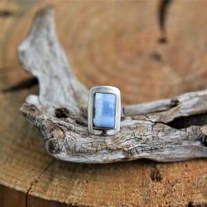 May include: A silver ring with a light blue rectangular stone set in a bezel setting.
