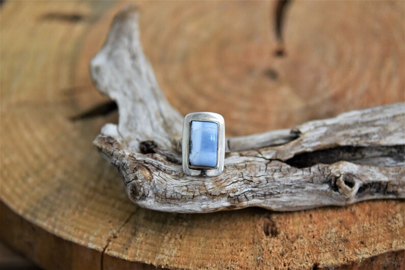 May include: A silver ring with a light blue rectangular stone set in a bezel setting.