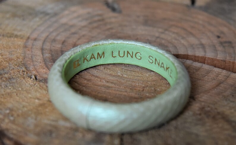 Pu&ograve; includere: Un braccialetto in pelle verde chiaro con il testo "KAM LUNG SNAKE" inciso in lettere dorate.