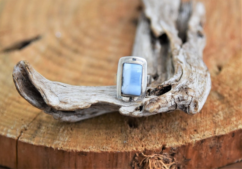May include: A silver ring with a light blue rectangular stone set in a bezel setting.