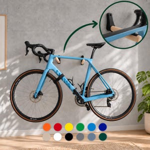 Può includere: Una bicicletta da corsa azzurra montata a parete con un supporto orizzontale nero e in legno chiaro. La bici presenta manubrio da corsa, ruote nere e un telaio con la scritta Canyon. Un inserto circolare mostra la staffa nera e il braccio in legno.