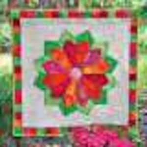 May include: A colorful patchwork quilt block with a flower design in shades of red, orange, pink, and green. The flower is surrounded by a green border and a red and green checkered border.