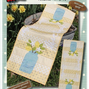 May include: A table runner quilt pattern featuring a mason jar with lemons and the text "Live Simply Blessed". The pattern is easy to make and is finished at 14 inches by 38 inches.