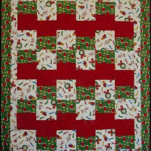 May include: A red, white, and green patchwork quilt with a Christmas theme. The quilt is made up of squares with different patterns, including presents, bells, and snowflakes.