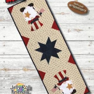 May include: A table runner sewing pattern featuring a patriotic gnome design. The pattern is 12 1/2 inches by 36 inches and is labeled as "Jelly Roll Friendly".
