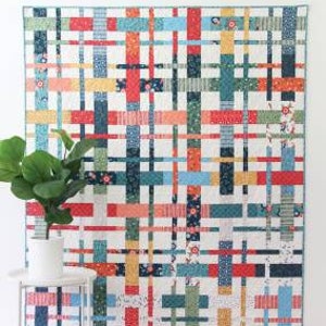 May include: A quilt pattern called "Plaidy Cake" by "Wuck Cluck Sew". The quilt is a layer cake or fat quarter quilt in 5 sizes. The quilt is made with a variety of colorful fabrics in a plaid pattern.