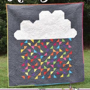 May include: A quilt pattern called "April Showers" featuring a white cloud with colorful raindrops on a gray background. The quilt pattern is designed by Running Doe Quilts for Villa Rosa Designs.