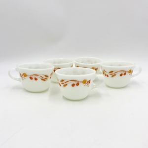Puede incluir: Juego de cuatro tazas de cerámica blanca con un diseño floral marrón y naranja. Las tazas tienen una forma redondeada y un asa en el lateral.