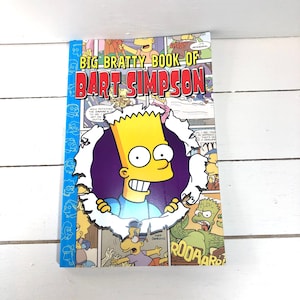 May include: A yellow and blue comic book cover featuring Bart Simpson from The Simpsons. The cover has a torn edge revealing Bart Simpson peeking out from behind the cover. The text on the cover reads "Big Bratty Book of Bart Simpson".