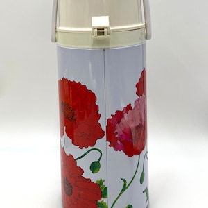 May include: A vintage white and red floral thermos with a white handle and lid. The thermos features a vibrant red poppy flower design on a white background. The thermos is approximately 10 inches tall.
