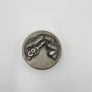 Op de afbeelding: Een zilveren metalen naaibox met een ontwerp van een schaar, draad en een knoop. De doos heeft de woorden "a stitch in time" gegraveerd.