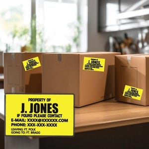 May include: Three cardboard boxes with yellow labels that read "PROPERTY OF J. JONES" and contact information. The boxes are on a wooden surface, with a kitchen in the background.